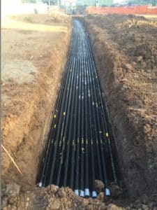 Champion Duct® RTRC fiberglass conduit installed in an open trench for direct-buried underground electrical distribution.