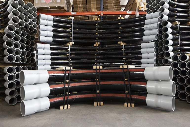 Stacks of fiberglass electrical conduit elbows.
