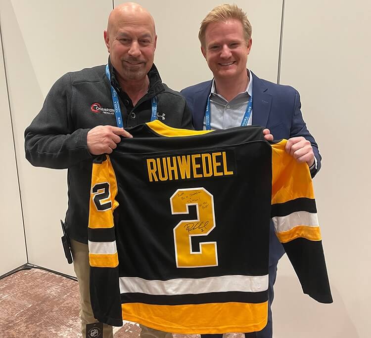 Two men display custom Ruhwedel hockey jersey.